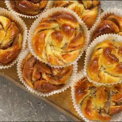 Nybakade bullar med mandelmassa, kanel och vallmofrön i pappersformar på en träbricka. Doftar ljuvligt!