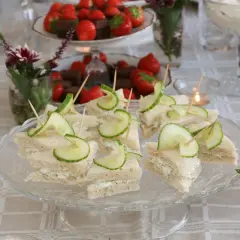 Smörgåsar med gurka och krämig fyllning, perfekta för ett afternoon tea recept. Jordgubbar och choklad i bakgrunden.