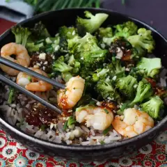 En skål med ris, räkor och broccoli, perfekt för ett snabbt och gott broccoli recept. Serveras med ätpinnar.