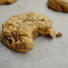 En bit tagen ur en nybakad chocolate chip cookie, med smält choklad som syns.