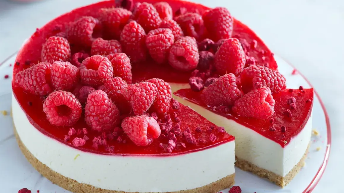 En läcker cheesecake i glas, toppad med färska hallon och hallonspegel. Perfekt för en somrig fika.