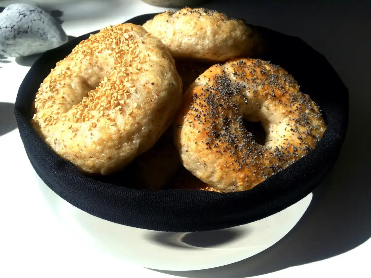 Färska bagels i en korg, en med sesamfrön, en med vallmofrön. Perfekt för ett enkelt bagels recept.