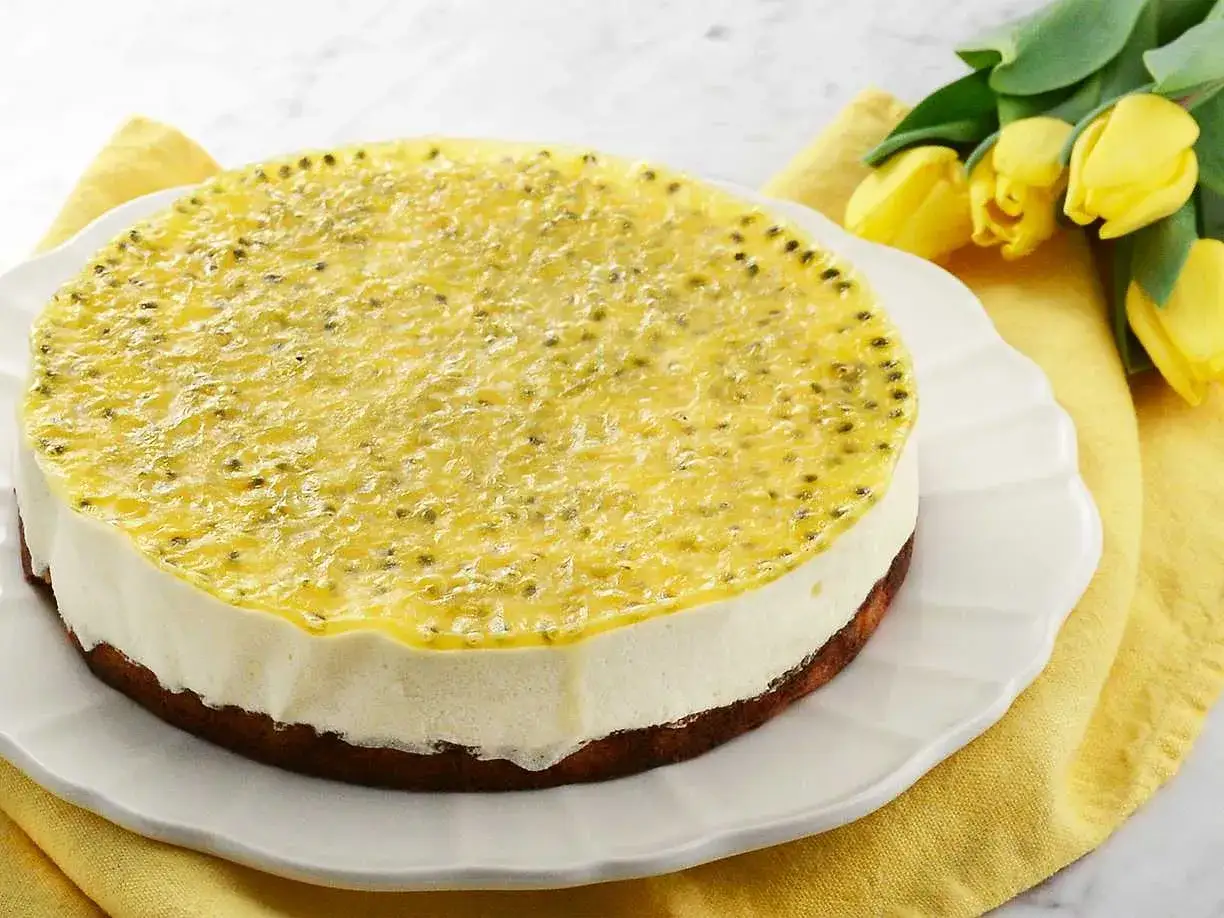 En läcker passionsfrukts-cheesecake påsk. Krämig vit fyllning med en glansig, gul passionsfruktsgelé på toppen.